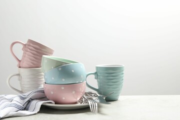 Beautiful ceramic dishware, cups and cutlery on light grey table