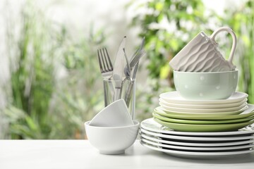 Beautiful ceramic dishware, cutlery and cup on white table outdoors, space for text