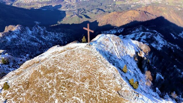 Pull-back drone footage of the cross on the summit of Pizzo Formico mountain in Lombardy, Italy