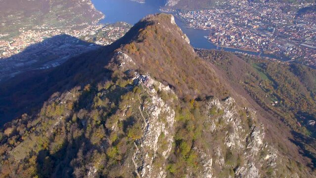 Aerial footage of Mount Barro mountain with Lecco city in the background on a sunny day, Italy