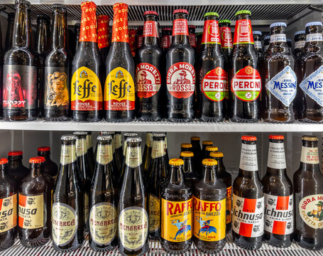 Beer in glass bottles of various types and brands in refrigerated counter. Italian, Sicilian and Sardinian beers and Leffe beer displayed for sale in cold weather