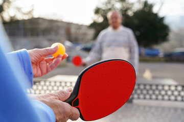 Mature couple playing table tennis in the garden.