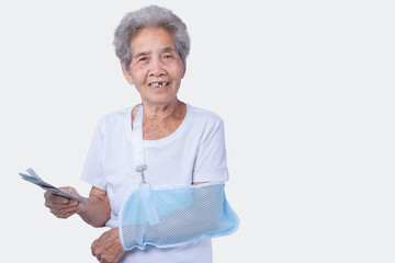 A sen woman with broken arm and wearing a sling with a smiling face and holding dollars for...