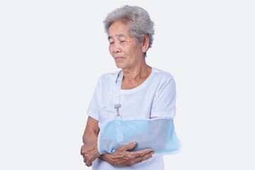 Close-up portrait of an 80s-year-old Senior woman with broken arm and wearing a sling isolated on a...