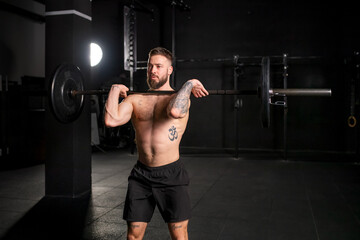 Fototapeta na wymiar Strong man performing front squat, barbell resting on front shoulders. Routine workout for physical and mental health.