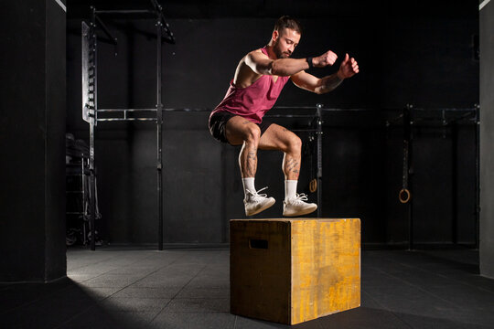 Man in sportwear jumping onto yellow box. Vertical box jumps workout. Routine workout for physical and mental health.