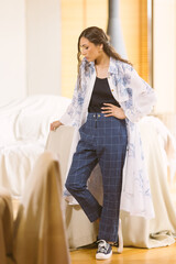 Fashionable confident woman wearing elegant suit, trousers posing in interior.