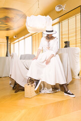 Elegant fashionable woman wearing summer white dress, straw hat, posing in stylish boho interior. - 791548161