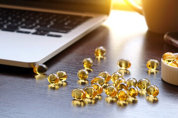 Close-up of many omega-3 oil capsules on a dark brown table against the backdrop of a pill container