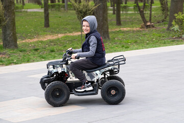 Happy six-year-old boy riding quad bike for kids.