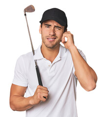 Young Hispanic man with golf club covering ears with hands.