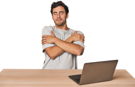 Hispanic young man working on laptop hugs, smiling carefree and happy.