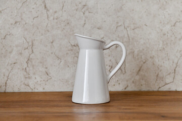 white ceramic vase on wooden surface with beige marble background 