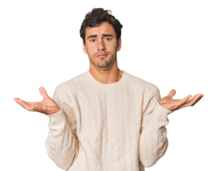 Young Hispanic man in studio doubting and shrugging shoulders in questioning gesture.