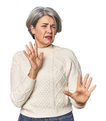 Caucasian mid-age female on studio background rejecting someone showing a gesture of disgust.