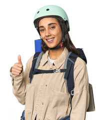 Hispanic young woman with mountain gear smiling and raising thumb up