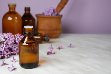 Lilac flower background with aroma therapy massage essential oil bottles. Side view. Space for text.