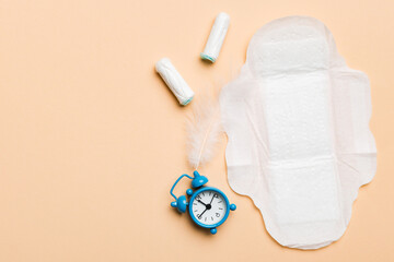 Ringing alarm clock with sanitary female tampons and menstrual sanitary pads. Medical concept of...