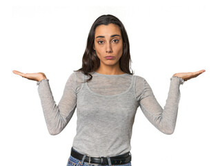 Hispanic young woman doubting and shrugging shoulders in questioning gesture.