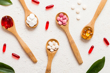 Vitamin capsules in a spoon on a colored background. Pills served as a healthy meal. Red soft gel vitamin supplement capsules on spoon - obrazy, fototapety, plakaty