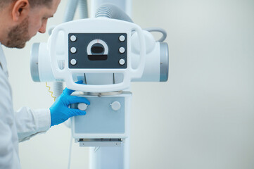 A male doctor works with an x-ray machine in a modern hospital. Medical equipment operator close-up in clinic