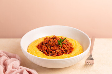 Polenta with ragu or meat and tomato sauce bolognese. Boiled cornmeal porridge.