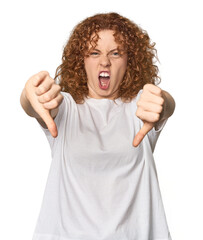 Young Caucasian redhead woman showing thumb down and expressing dislike.