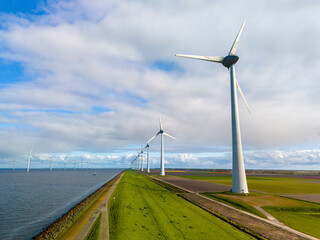 A picturesque scene of sleek wind turbines standing tall in a row next to a tranquil body of water, harnessing renewable energy on a bright Spring day
