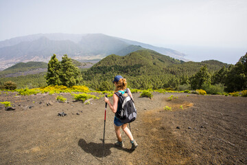 A young woman walking towards Birigoyo peak, La Palma Island, Canary Islands. - obrazy, fototapety, plakaty