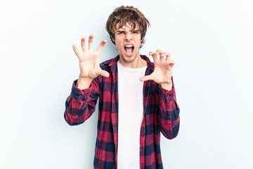 Young caucasian man isolated on blue background showing claws imitating a cat, aggressive gesture.