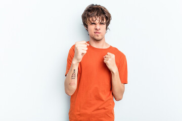 Young caucasian man isolated on blue background showing fist to camera, aggressive facial...