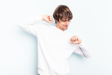 Young caucasian man isolated on blue background stretching arms, relaxed position.