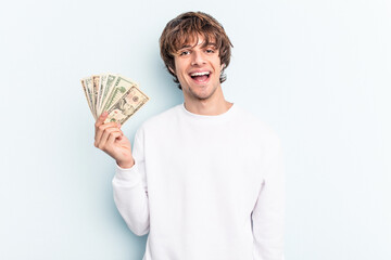 Young caucasian man holding banknotes isolated on blue background