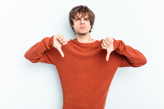 Young caucasian man isolated on blue background showing a dislike gesture, thumbs down. Disagreement concept.