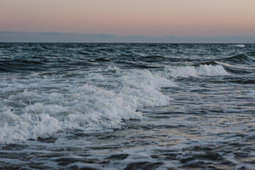 Waves on the sea on a cloudy day at sunset. Calm weather on the ocean. The horizon of the sea.