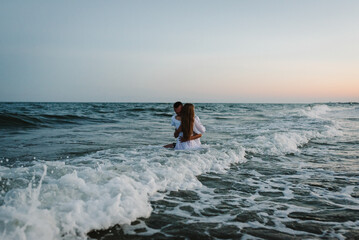 Swimming. Portrait of a beautiful man and woman in wet clothes in sea. Couple hugging and kissing...