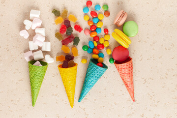 Different colorful candies, lollipops, marshmallows and macaroons in candy cane. Flat lay sweets on light background. Top view