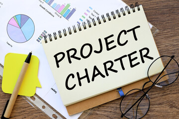 PROJECT CHARTER office desk, financial charts. words on the page
