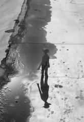 Black and white photograph of a human figure's reflection in a puddle.Minimal creative weather concept.Flat lay