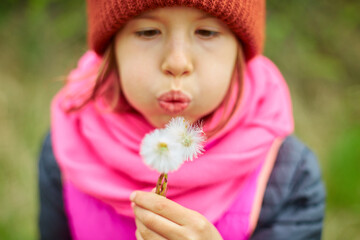 Young Girl Blowing Dandelion Seeds During a Sunny Day at the Park