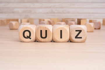 the word QUIZ is elegantly displayed on a beige hardwood rectangle block