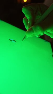 A video showing a person writing on various green screens and surfaces with a pen, including a tablet with a green screen. The focus is on the act of writing and creativity