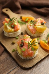 Tasty canapes with salmon served on wooden table, closeup