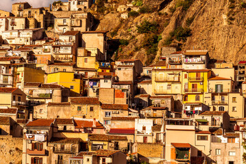 old mediterranean mountain dense town with levels of yellow houses and terraces on a mountain in evening light, vintage european village on a rock