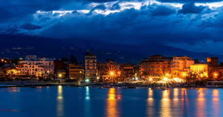 evening or night landscape of evening town coastline in golden lights and sea gulf with calm water...