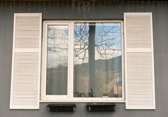 white shutters on a window on a gray building
