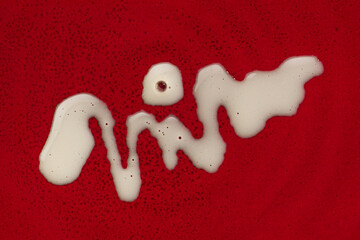 White cosmetic cream milk stain drops on burgundy dark red background