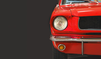 Front view of a vintage red car. Headlight. Classic car. Copy space. Dark background.	