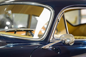 Detail of a vintage car. Rearview mirror. Windshield and wiper. Dark blue colored car. Classic. 