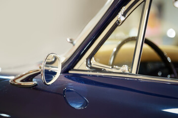 Side view of a vintage car's rearview mirror. Dark blue colored car. Classic. Selective focus.